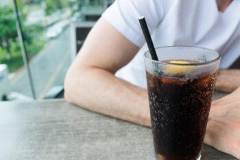 Close-up of unrecognizable white man at restaurant with drink served with paper straw